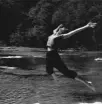 a girl jumping into the creek with arms and legs extended